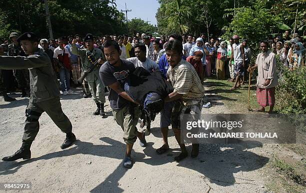 Relatives carry the body of a man who was killed by suspected separatists in Thailand's restive southern Narathiwat province on April 14, 2010. The...