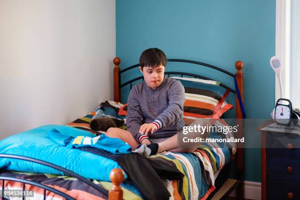 authentic boy of 12 years old with down syndrome in daily lives trying to get dressed - teen packing suitcase stock pictures, royalty-free photos & images