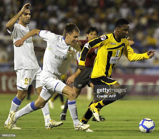 Bunyodkor's Ruslan Melziddinov and Joao Victor Brun approach Al-Ittihad's Mohammed Nur as he advances with the ball during their AFC Champions League...