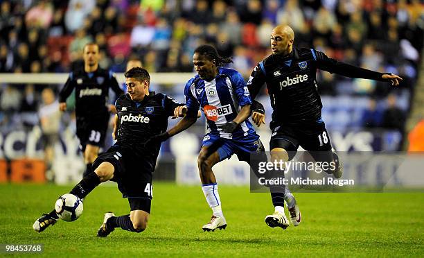 Joel Ward and Anthony Vanden Borra of Portsmouth challenge Hugo Rodallega of Wigan during the Barclays Premier League match between Wigan Athletic...