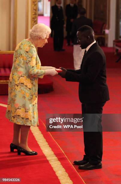 Mr. Gift Chansa from Zambia receives his Young Leaders Award from Queen Elizabeth II during the Queen's Young Leaders Awards Ceremony at Buckingham...