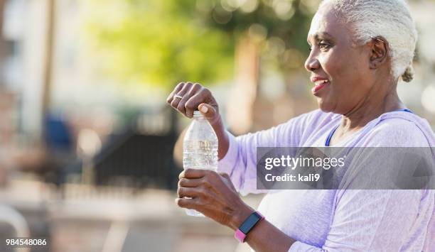 senior african-american woman opening water bottle - open workouts stock pictures, royalty-free photos & images