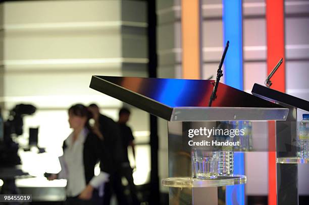 In this handout image provided by ITV1, People walk by a glass of water sitting next to a speaker's stand as the stage is prepared for the first...