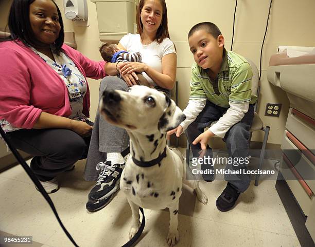 Nurse Care Technician Valerie Walker, Tabitha Lopez, her baby Tristan Lopez and her son Tyler Lopez play with Lacey the Dalmamtion of "101 Dalmations...