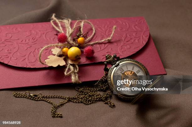 purple envelope with the old watch on a brown surface - brown envelope stock pictures, royalty-free photos & images