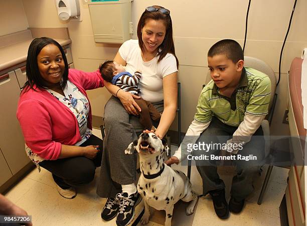 Nurse Care Technician Valerie Walker, Tabitha Lopez, her baby Tristan Lopez, and her son Tyler Lopez play with Lacey the Dalmatiian of '101'...