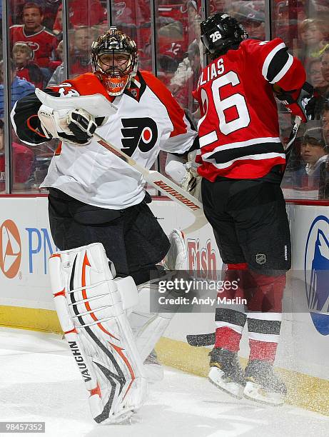 Patrik Elias of the New Jersey Devils jumps to avoid contact with goaltender Brian Boucher of the Philadelphia Flyers at the boards in Game One of...