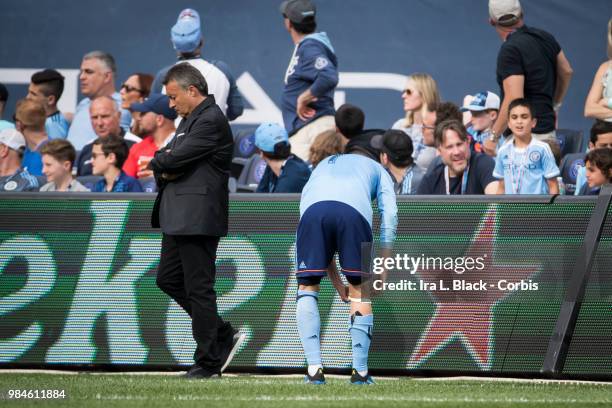 David Villa of New York City waits on the sideline to get attended by physician for injury while head coach Domenec Torrent of New York City waits...
