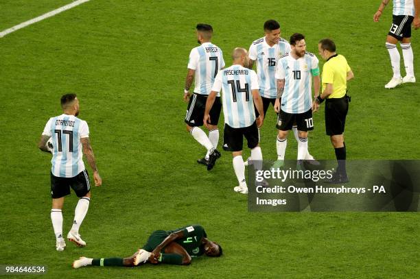 Nigeria's Wilfred Ndidi holds his leg as he lies on the pitch as Argentina's Lionel Messi speaks with match referee Cuneyt Cakir during the FIFA...