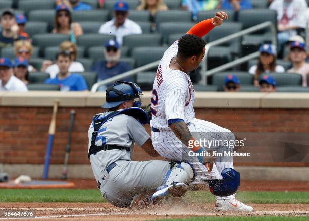 Dominic Smith of the New York Mets scores a run against Austin Barnes of the Los Angeles Dodgers at Citi Field on June 24, 2018 in the Flushing...