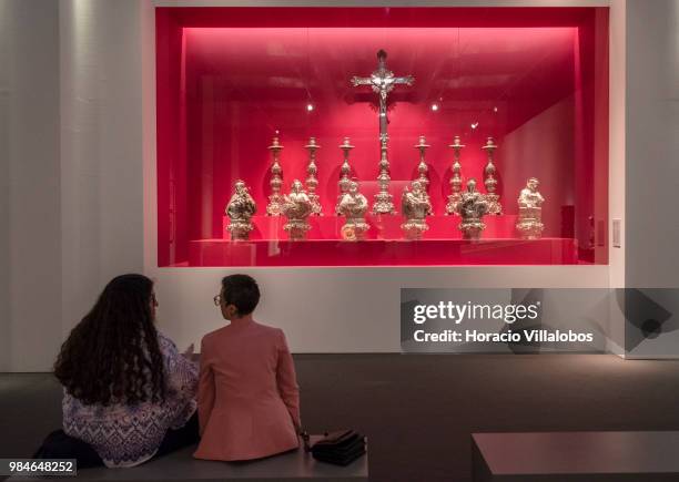 Visitors sit in front of eligious elements on display at "Na Rota Das Catedrais - Construcoes E Identidades" exhibition in D. Luis I gallery of...