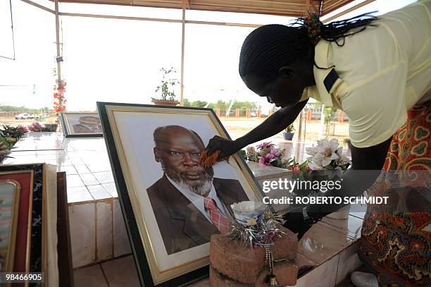 Woman quietly cleans the glass of a framed photograph of John Garang, a southern Sudan rebel leader who founded the Sudan People's Liberation...