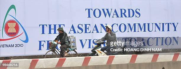 Cyclists ride past a poster marking the 16th summit of the Association of Southeast Asian Nations on a road in Hanoi on April 9, 2010. ASEAN leaders...