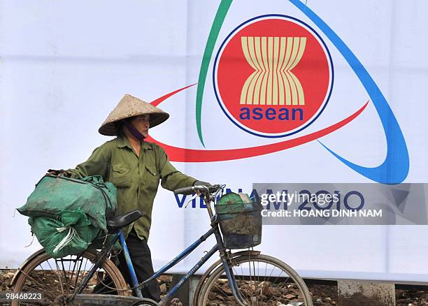 Recyclable-items collector walks past a poster marking the 16th summit of the Association of Southeast Asian Nations on a road in Hanoi on April 9,...