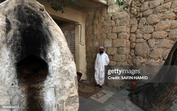 An Iraqi Yazidi man stands outside Lalish temple in a valley near Dohuk, 430 km northwest of the capital Baghdad, on June 24, 2018. At the Yazidis'...