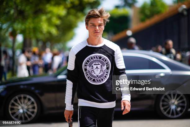 Oliver Cheshire wears a Balmain black and white pull over, outside Balmain, during Paris Fashion Week - Menswear Spring-Summer 2019, on June 24, 2018...