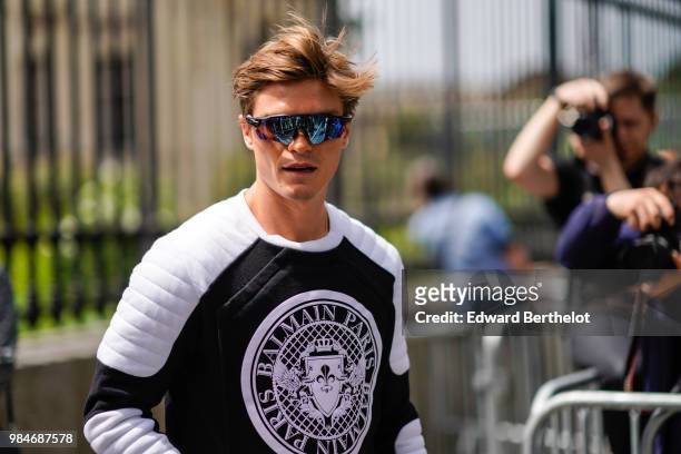 Oliver Cheshire wears a Balmain black and white pull over, outside Balmain, during Paris Fashion Week - Menswear Spring-Summer 2019, on June 24, 2018...