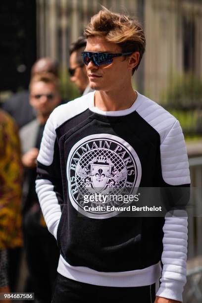 Oliver Cheshire wears a Balmain black and white pull over, outside Balmain, during Paris Fashion Week - Menswear Spring-Summer 2019, on June 24, 2018...