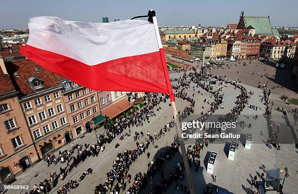 Polish flag adorned with a black strip flies high above mourners waiting in a snaking line to pay their last respects at the coffins of late Polish...