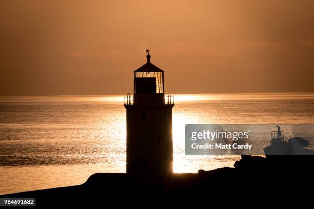 The sun sets at Godrevy Lighthouse near Gwithian on June 26, 2018 in Cornwall, England. Parts of the UK are currently basking in heatwave...