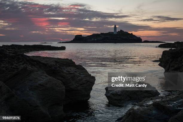 The sun sets at Godrevy Lighthouse near Gwithian on June 26, 2018 in Cornwall, England. Parts of the UK are currently basking in heatwave...