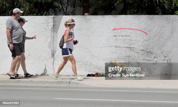 People walk past the site of a crash on May 12 where a Tesla Model S sedan crashed into a concrete wall in Ft. Lauderdale, Fla. The driver of the...