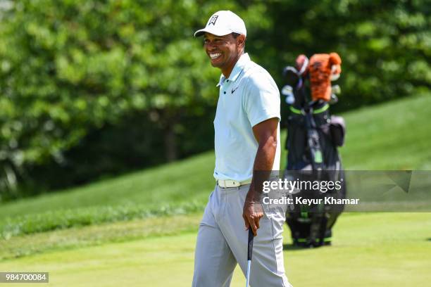 Tiger Woods smiles while testing a TaylorMade Ardmore 3 mallet putter on the 18th hole during practice for the Quicken Loans National at TPC Potomac...