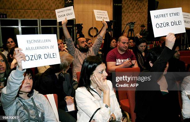 Gay rights activists hold placards which translate as " Don't hate, apologise " as they protest against Turkish State Minister in Charge of Family...