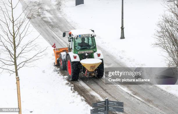 Tractor equipped with a snowplow clearing a street from snow and ice in the town of Irsee, Germany, 17 January 2018. Photo: Peter Kneffel/dpa