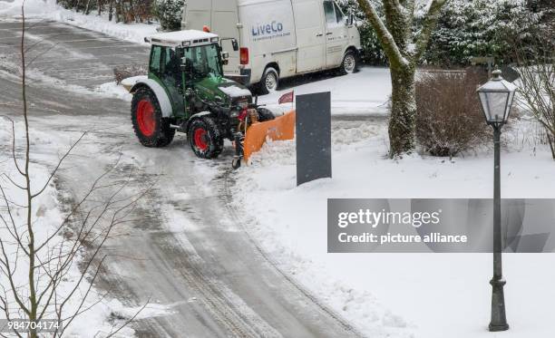 Tractor equipped with a snowplow clearing a street from snow and ice in the town of Irsee, Germany, 17 January 2018. Photo: Peter Kneffel/dpa