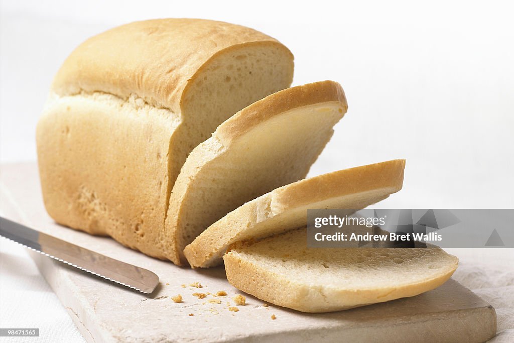 White loaf on breadboard with slices and knife
