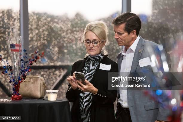 Paula Hutchins, left, and Mike Hutchins look at results during a Republican gubernatorial primary runoff election watch party at Spirit...