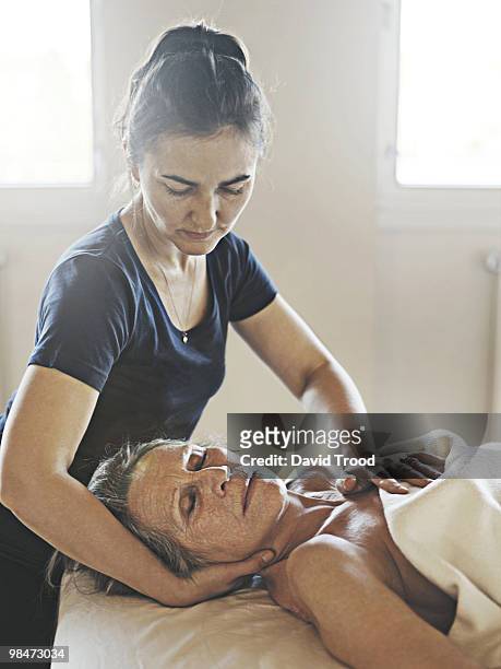 elderly woman receiving healing massage. - david trood stock-fotos und bilder