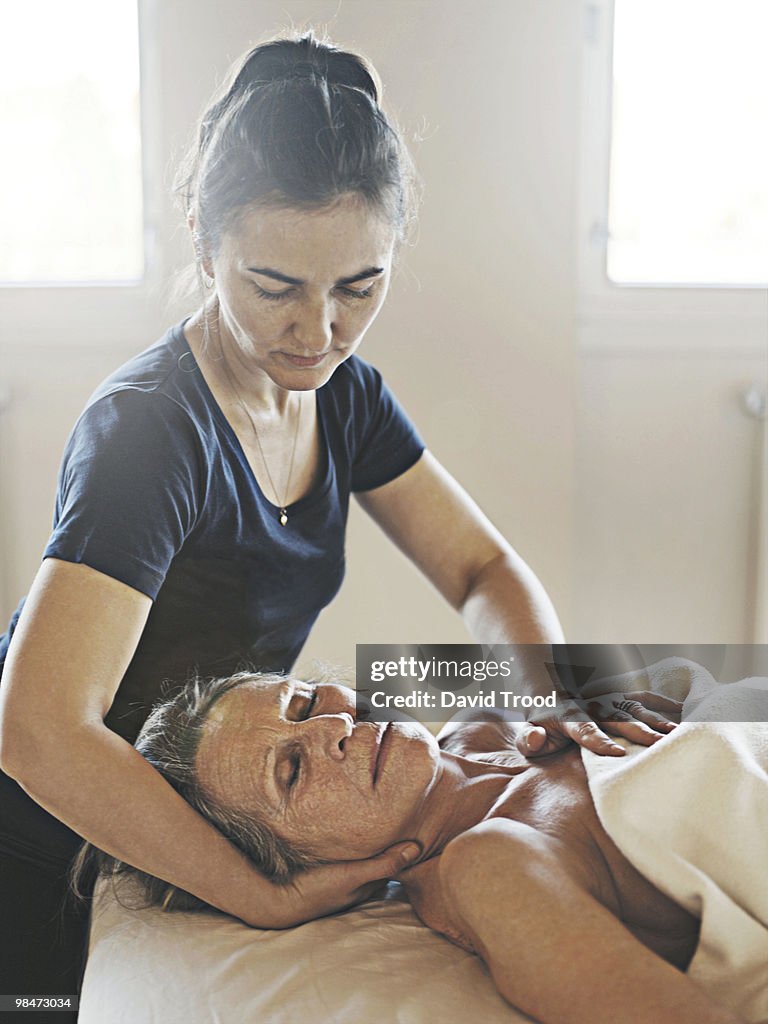Elderly woman receiving healing massage.
