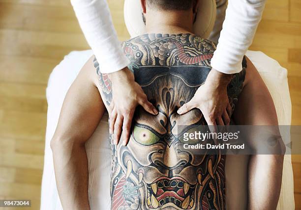massaging a tatoo - david trood stock pictures, royalty-free photos & images