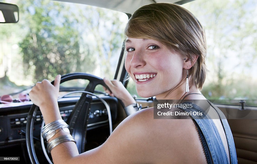 Young woman driving car, smiling