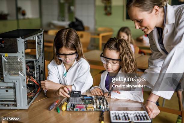 maestro feliz asistiendo a la escuela de niñas en la reparación de componentes de la computadora en el aula. - science fotografías e imágenes de stock