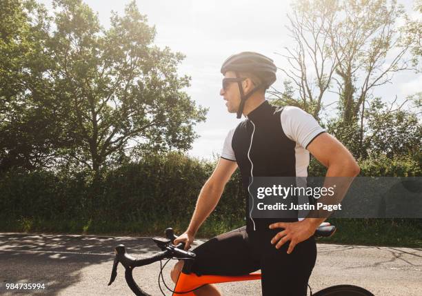 cyclist resting by road side - man bicycle stock pictures, royalty-free photos & images
