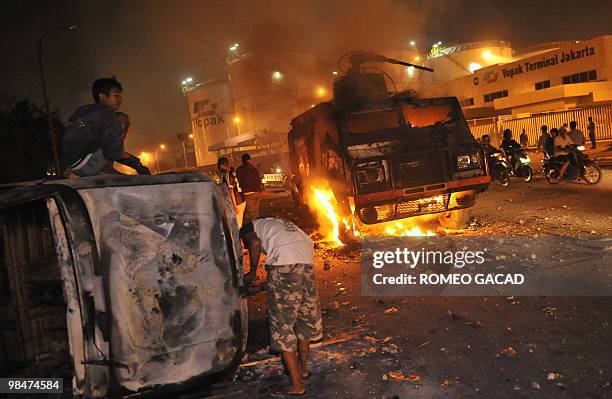 Looters damaged burnt vehicles while a police water canon truck is in fire after some 70 police vehicles were torched by demonstrators during clashes...