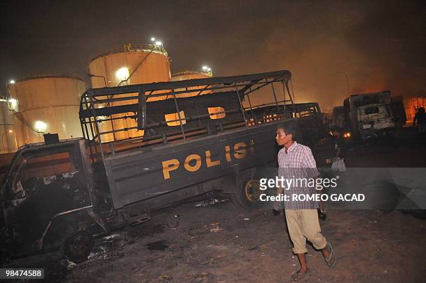 Resident walks past a burnt police van after some 70 police vehicles were torched by demonstrators during clashes with police near a cemetery outside...