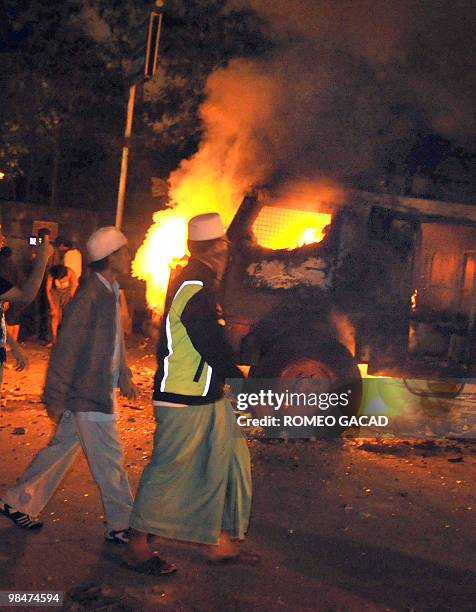 Residents look at a burning police water canon truck after some 70 police vehicles were torched by demonstrators during clashes with police near a...