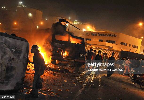 Looters damaged burnt vehicles while a police water canon truck is in fire after some 70 police vehicles were torched by demonstrators during clashes...