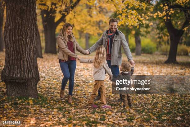 happy family having fun while playing ring-around-the-rosy in autumn day. - ring around the rosy stock pictures, royalty-free photos & images