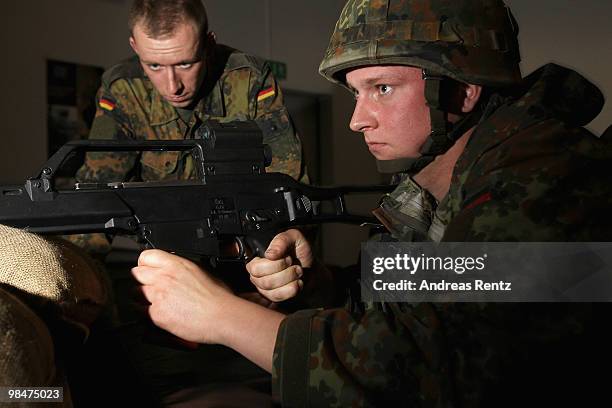 Young recruit of the German Bundeswehr shoots with a prepared G36 assault rifle as a trainer assists during a practice at the 'Schiesskino', a shoot...