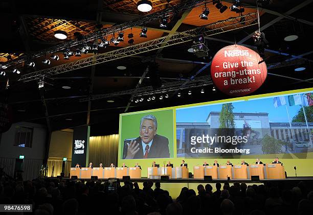Peter Brabeck-Letmathe, chairman of Nestle SA, speaks on a large screen under a Greenpeace sign at the company's shareholders' meeting in Lausanne,...