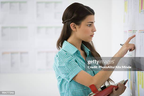 female college student checking bulletin board, holding agenda - college admission stock pictures, royalty-free photos & images