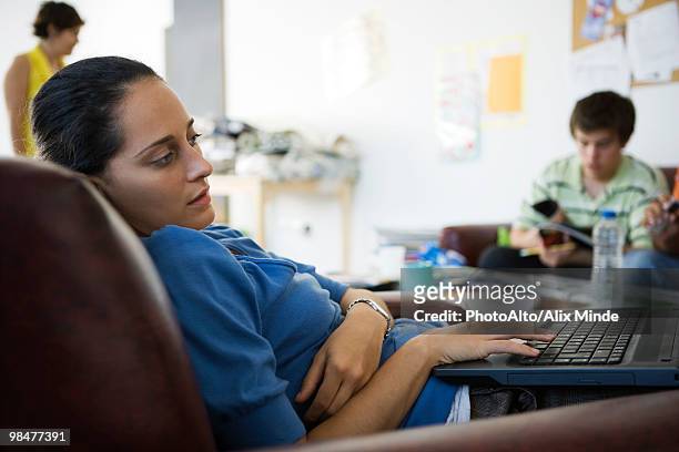 female college student lounging in armchair using laptop computer - bad posture fotografías e imágenes de stock