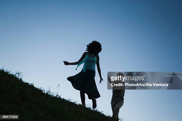 young woman playfully running away from man in pursuit - pursuit stock pictures, royalty-free photos & images