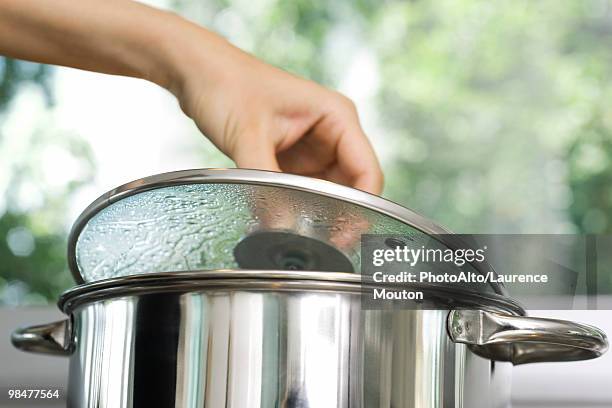 person removing lid from cooking pot - pfanne stock-fotos und bilder