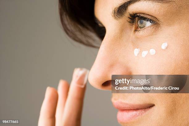 young woman applying undereye cream - concealer foto e immagini stock